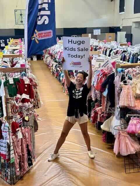 Employee with Huge Kids Sale Today Sign